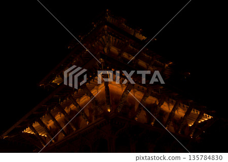 The intricate woodwork and underside of the roof of an illuminated Nepalese temple 135784830