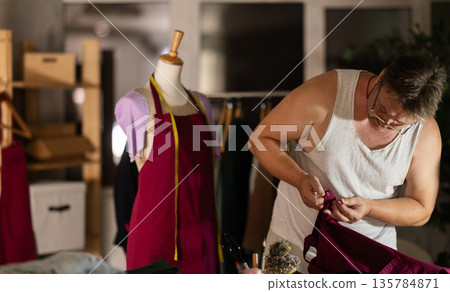 Man tailor repairs clothes, provides services for restoration of damaged cloth Man tailor repairs clothes, provides services for restoration of damaged cloth 135784871