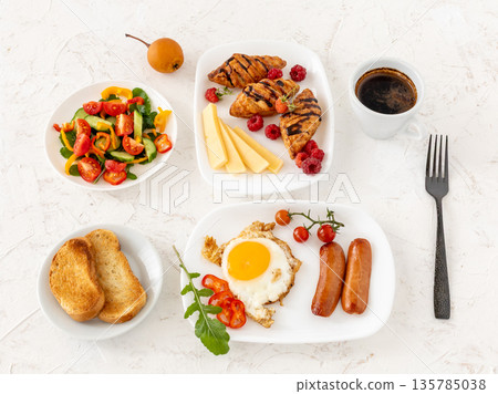 Fried egg and grilled sausages served with fresh tomatoes, sliced bell pepper, cucumbers. Fried egg and grilled sausages served with fresh tomatoes, sliced bell pepper, cucumbers. 135785038