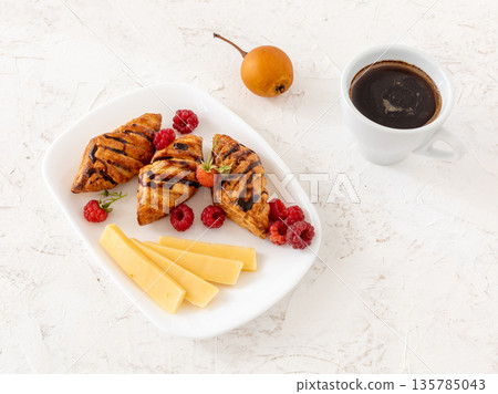 Croissants. sliced cheese and raspberries with a cup of coffee. 135785043