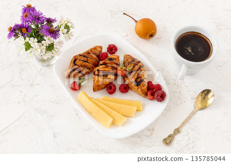 Croissants. sliced cheese and raspberries with a cup of coffee. Croissants. sliced cheese and raspberries with a cup of coffee. 135785044