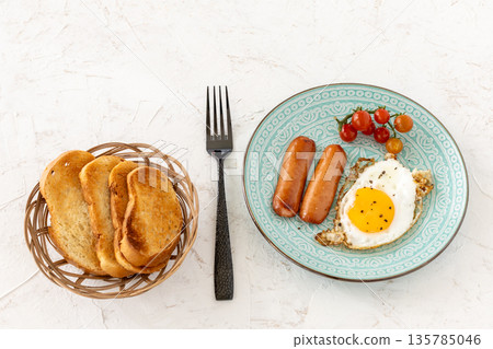 Fried egg and grilled sausages served with fresh tomatoes on the plate. Fried egg and grilled sausages served with fresh tomatoes on the plate. 135785046