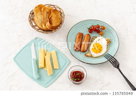 Fried egg and grilled sausages served with fresh tomatoes on the plate. Fried egg and grilled sausages served with fresh tomatoes on the plate. 135785049