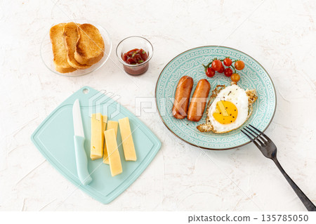 Fried egg and grilled sausages served with fresh tomatoes on the plate. 135785050