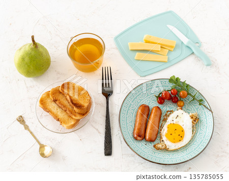 Fried egg and grilled sausages with a cup of tea. Fried egg and grilled sausages with a cup of tea. 135785055