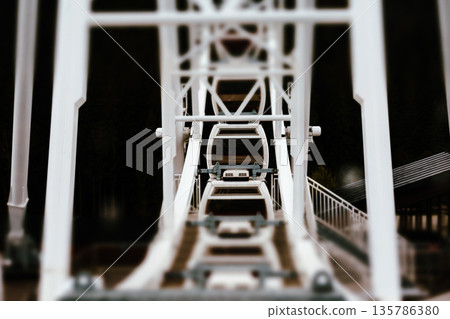 A low-angle, abstract shot from inside a Ferris wheel structure, creating an immersive, architectural view. The steel framework  135786380