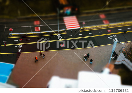 Top-down view of a city street intersection with a tilt-shift effect, creating a miniature world aesthetic. Urban life from a high angle with selective focus, for logistics, creative design concepts. Top-down view of a city street intersection with a tilt-shift effect, creating a miniature world aesthetic. Urban life from a high angle with selective focus, for logistics, creative design concepts. 135786381
