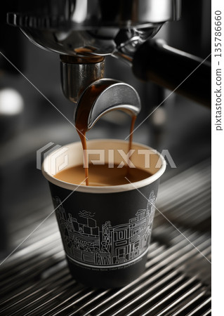 Espresso flowing into black paper cup. Espresso extracting from a commercial machine, rich crema pouring into a black paper cup Espresso flowing into black paper cup. Espresso extracting from a commercial machine, rich crema pouring into a black paper cup 135786660