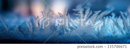 Frosty ice crystal patterns forming on blue glass. Blue frosty ice forming sharp, sparkling crystal patterns on a cold surface 135786671