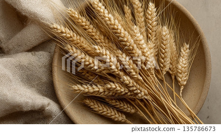 Golden wheat ears are filling a ceramic bowl, representing agriculture and natural ingredients. Golden wheat ears filling bowl symbolizing harvest and food 135786673