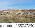 A large, open field with a few houses in the distance 135787250