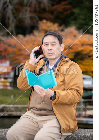 A man using a smartphone in an autumn park 135787861