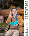 A man using a smartphone in an autumn park 135787862