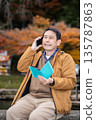 A man using a smartphone in an autumn park 135787863