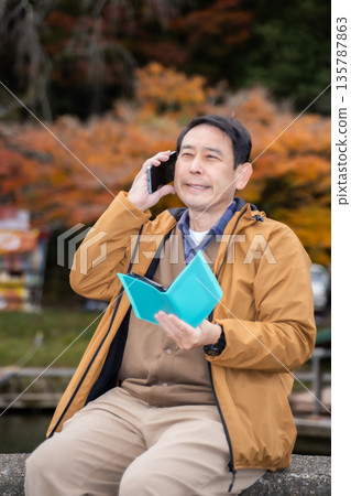 A man using a smartphone in an autumn park A man using a smartphone in an autumn park 135787863