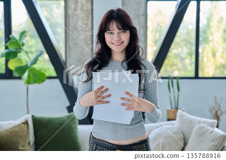 Smiling young woman with business study important papers standing in home interior 135788916