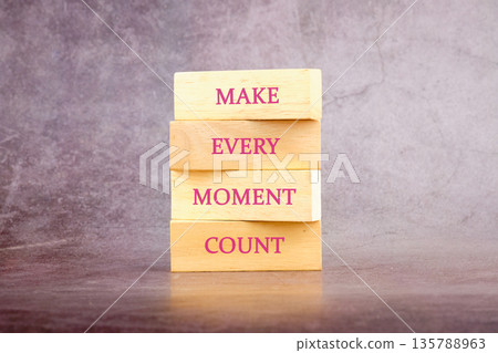 A stack of wooden blocks displaying the message Make Every Moment Count on a textured grey surface, a gentle reminder to cherish lifes present gifts A stack of wooden blocks displaying the message Make Every Moment Count on a textured grey surface, a gentle reminder to cherish lifes present gifts 135788963