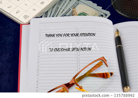 Open ledger, a gratitude message for customer satisfaction. Fountain pen, eyeglasses, financial tools on a dark desk. Clearly, dedicated daily work 135788992