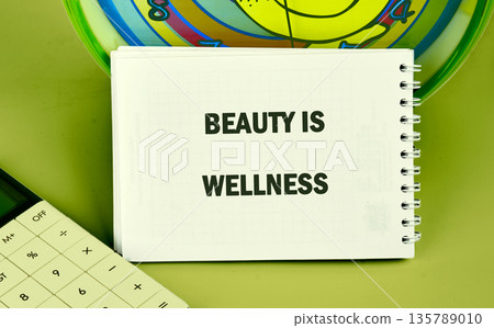 A pristine white spiral notebook gracefully rests on a tranquil green surface, boldly proclaiming the uplifting message Beauty Is Wellness A pristine white spiral notebook gracefully rests on a tranquil green surface, boldly proclaiming the uplifting message Beauty Is Wellness 135789010