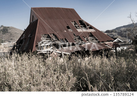 An abandoned house on the verge of collapse due to corroding tin roof 135789124