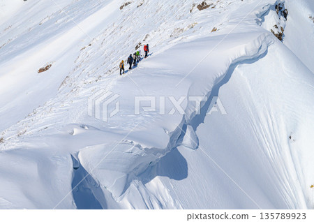 雪山攀登：登山者經過巨大的雪簷（谷川岳） 135789923