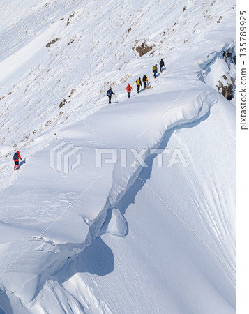 Snowy mountain climbing: Climbers passing by a huge snow cornice (Tanigawadake) 135789925