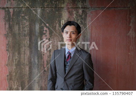 Portrait of a serious businessman standing against a wall 135790407
