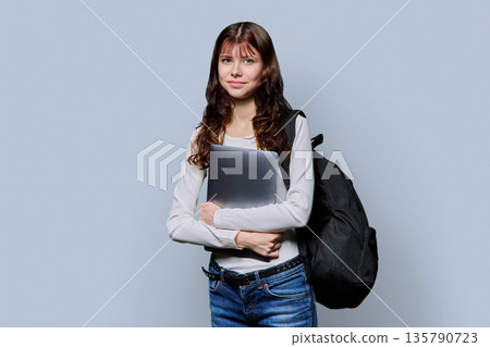 Portrait of beautiful girl teenage student with backpack, laptop on gray background 135790723
