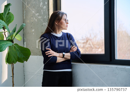 Middle-aged confident serious woman looking at window 135790737