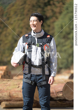 A smiling man wearing work clothes and holding a helmet A smiling man wearing work clothes and holding a helmet 135790812