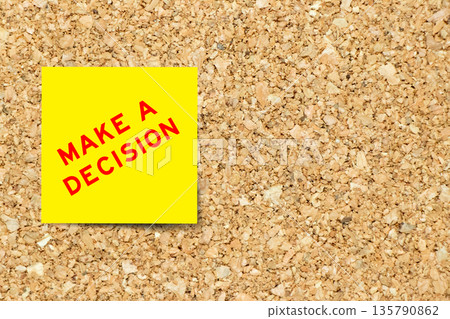 Yellow note paper with word make a decision on cork board background with copy space 135790862