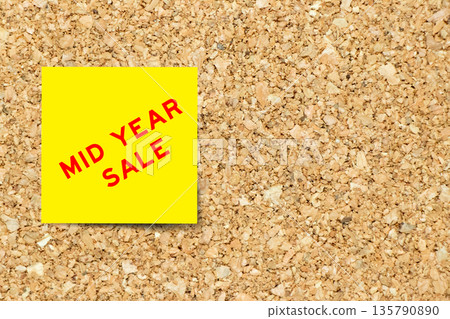 Yellow note paper with word mid year sale on cork board background with copy space 135790890