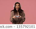 Young Female Gamer Celebrating Victory While Playing Video Games On Pink Studio 135792101