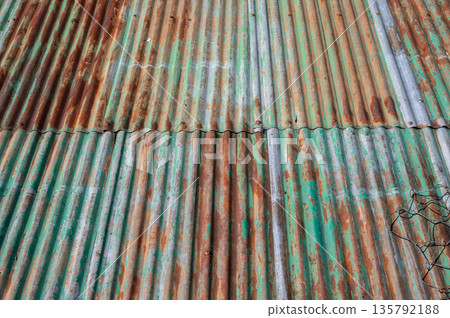 An old rusty metal sheet roof textured. Rust is an iron oxide formed by the reaction of iron and oxygen in the catalytic presence of water or air moisture. An old rusty metal sheet roof textured. Rust is an iron oxide formed by the reaction of iron and oxygen in the catalytic presence of water or air moisture. 135792188