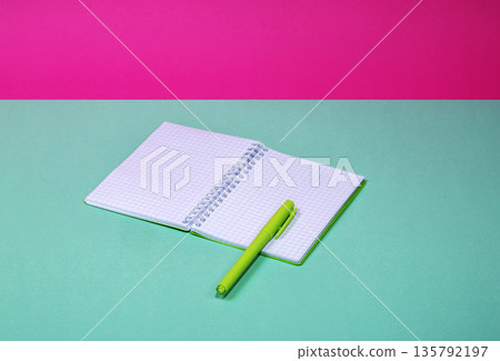 An open notebook and a green pen on a colored background. An open notebook and a green pen on a colored background. 135792197