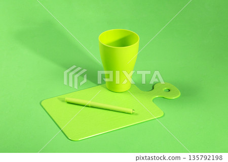 Green cup, green pen, green chalkboard on a green background 135792198