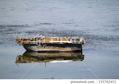 lonely fishing boat docked in calm lake. wooden fishing boat in a still lake water. image of wooden fishing boat moored on the shore. space for text. lonely fishing boat docked in calm lake. wooden fishing boat in a still lake water. image of wooden fishing boat moored on the shore. space for text. 135792452