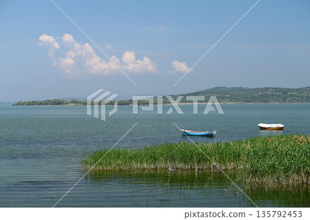 lonely fishing boat docked in calm lake. wooden fishing boat in a still lake water. image of wooden fishing boat moored on the shore. space for text. lonely fishing boat docked in calm lake. wooden fishing boat in a still lake water. image of wooden fishing boat moored on the shore. space for text. 135792453