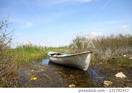 lonely fishing boat docked in calm lake. wooden fishing boat in a still lake water. image of wooden fishing boat moored on the shore. space for text. lonely fishing boat docked in calm lake. wooden fishing boat in a still lake water. image of wooden fishing boat moored on the shore. space for text. 135792457