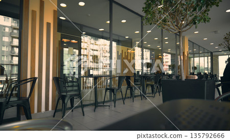 Contemporary outdoor restaurant seating featuring black metal chairs and glass storefront 135792666