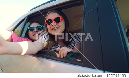 Happy family, girls driving car cheerfully waving their hands out car window, smiling face child kid, summer van ride party. friendship travel joy, sunglasses reflecting sky, youth and happiness Happy family, girls driving car cheerfully waving their hands out car window, smiling face child kid, summer van ride party. friendship travel joy, sunglasses reflecting sky, youth and happiness 135793463