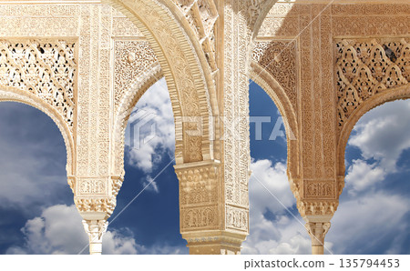Arches in Islamic (Moorish)  style (against the background of a beautiful sky with clouds) in Alhambra, Granada, Spain 135794453