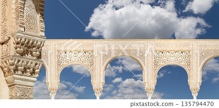 Arches in Islamic (Moorish) style (against the background of a beautiful sky with clouds) in Alhambra, Granada, Spain Arches in Islamic (Moorish) style (against the background of a beautiful sky with clouds) in Alhambra, Granada, Spain 135794470