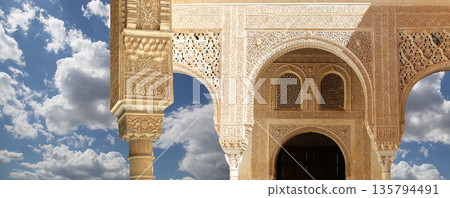 Arches in Islamic (Moorish) style (against the background of a beautiful sky with clouds) in Alhambra, Granada, Spain 135794491