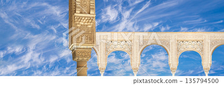 Arches in Islamic (Moorish) style (against the background of a beautiful sky with clouds) in Alhambra, Granada, Spain Arches in Islamic (Moorish) style (against the background of a beautiful sky with clouds) in Alhambra, Granada, Spain 135794500