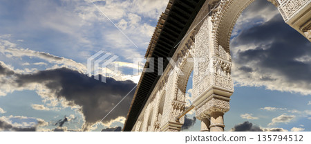 Arches in Islamic (Moorish) style (against the background of a beautiful sky with clouds) in Alhambra, Granada, Spain 135794512