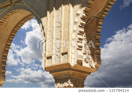 Arches in Islamic (Moorish) style (against the background of a beautiful sky with clouds) in Alhambra, Granada, Spain Arches in Islamic (Moorish) style (against the background of a beautiful sky with clouds) in Alhambra, Granada, Spain 135794514