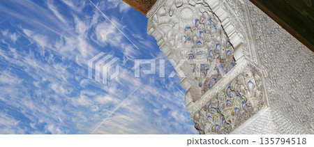 Arches in Islamic (Moorish) style (against the background of a beautiful sky with clouds) in Alhambra, Granada, Spain Arches in Islamic (Moorish) style (against the background of a beautiful sky with clouds) in Alhambra, Granada, Spain 135794518