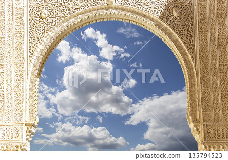 Arches in Islamic (Moorish) style (against the background of a beautiful sky with clouds) in Alhambra, Granada, Spain Arches in Islamic (Moorish) style (against the background of a beautiful sky with clouds) in Alhambra, Granada, Spain 135794523