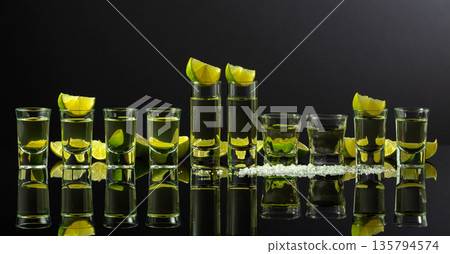 Tequila shots with lime slices and salt on a black reflective background. 135794574